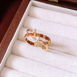 Macro shot of gold double-layer star ring with chain detail and brown leather inlay