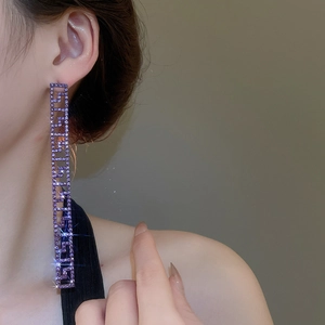 Dettaglio di orecchini lunghi quadrati con cristalli viola e frange in argento