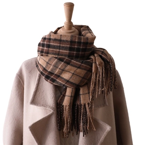 Classic brown plaid cashmere-like scarf with fringe on a beige coat mannequin