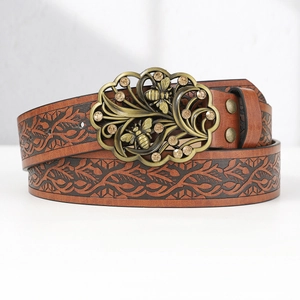 Close-up of vintage brown leather belt with embossed leaf pattern and bee buckle