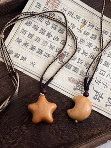 Detailed macro view of handmade wooden star and moon pendants on braided cord necklaces