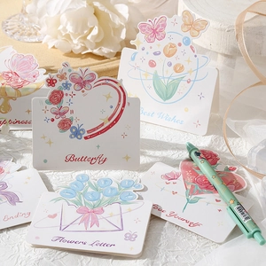 Flat lay of multiple floral greeting cards with artistic illustrations on white fabric
