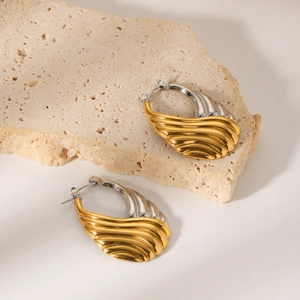Two-tone wavy hoop earrings in gold and silver stainless steel on stone display