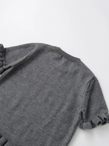 Close-up of ribbed crewneck and ruffle lettuce trim cuffs on grey knit sweater