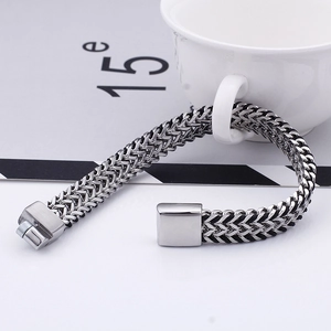 Macro detail of silver-black braided steel bracelet showing industrial clasp texture