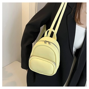 Pale yellow PU leather mini backpack shown on a model with silver metal zipper detail