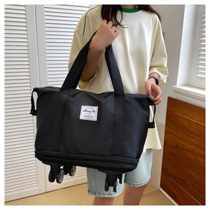 Detail of expandable black travel bag featuring rolling wheels and reinforced handles
