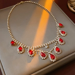 Detail of a gold necklace with sparkling rhinestones and red teardrop pendant on a display
