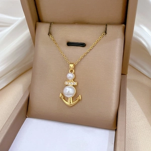 Dettaglio del ciondolo ad ancora dorata con perle e cristalli nella scatola regalo