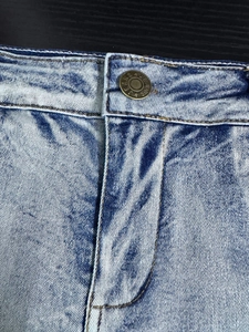 Vista macro dettagliata del tessuto denim e del bottone metallico sui pantaloncini blu