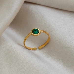 Gros plan d'une bague dorée torsadée ornée d'une malachite verte ronde sur soie