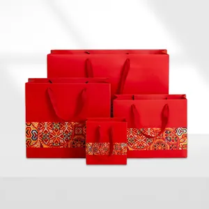 Four red Chinese style paper gift bags in varying sizes with traditional floral patterns