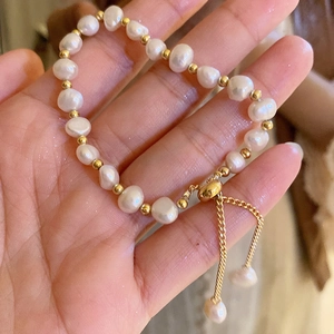 Detail of adjustable gold plated freshwater pearl bracelet with tassel held in hand