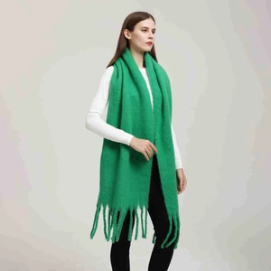Dettaglio di sciarpa verde simil-cashmere con trama morbida e nappe lunghe decorative