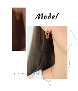 Close-up of gold-plated heart and bow earrings worn by a model in a fashion style