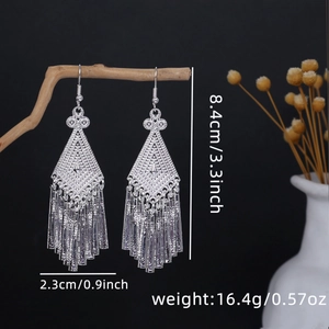 Detailed view of silver ethnic tassel earrings on wood branch with dimensions 8.4cm x 2.3cm