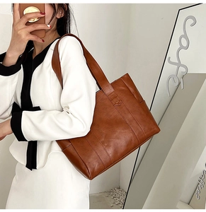Brown PU leather tote bag with minimalist stitching shown on model shoulder