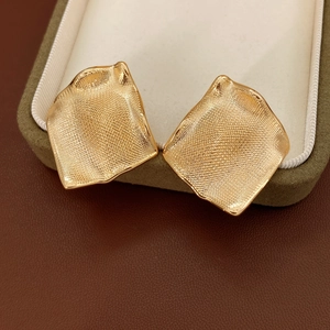 Vue détaillée de boucles d'oreilles géométriques dorées avec texture de grille tissée
