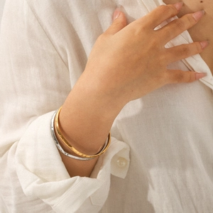 Close-up of hammered two-tone gold and silver layered open cuffs on model wrist