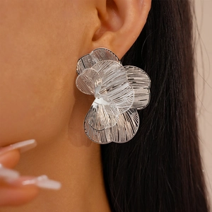 Close-up of oversized silver hollow flower petal earrings with intricate metal mesh texture