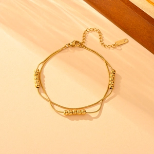 Close-up of golden double-layered snake chain bracelet with gold beads in sunlight