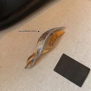 Detailed macro view of dual-tone leaf brooch with zircon pavé and brushed gold finish