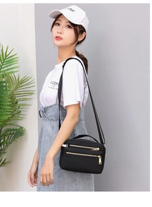 Detail of water-resistant nylon crossbody bag with three golden zippers and adjustable strap