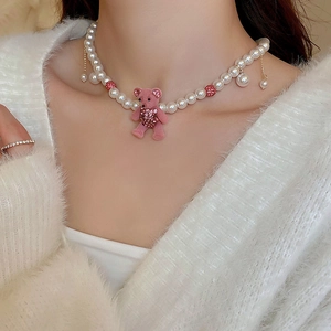 Close-up of pink flocked bear pendant with sparkling crystals and faux pearl necklace