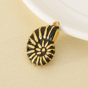 Pendentif coquillage doré avec émail noir sur un fond en tissu texturé beige neutre