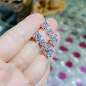 Gros plan de boucles d'oreilles pendantes argentées avec cristaux carrés et ronds
