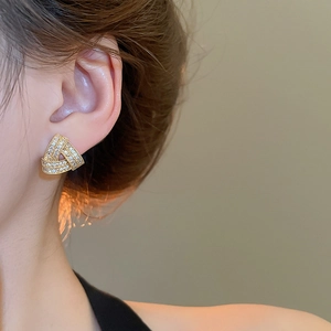Detailed close-up of geometric triangle stud earrings with zircons on model ear
