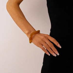 Detailed view of amber acrylic irregular bangle on wrist with elegant texture