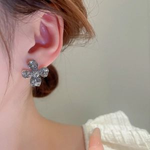 Detail of flower stud earring with hammered texture and center crystal on ear lobe
