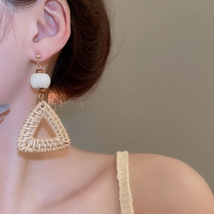 Detail view of Bohemian woven triangle earrings with white beads on a model