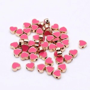 Macro shot of 8mm pink heart enamel beads with gold metal frames for DIY jewelry crafts