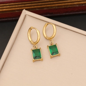 Close-up of square emerald zircon earrings with gold plating on a beige jewelry tray