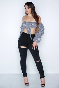 Detail of high waist ripped skinny jeans with off-shoulder plaid top on a model