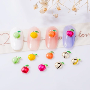 Colorful peach-shaped alloy nail charms in gold and silver on white background