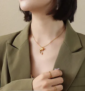 Detail of 18k gold plated dolphin pendant necklace worn with a matching chain ring