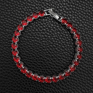 Detailed top view of a ruby red tennis bracelet with silver prong setting on leather