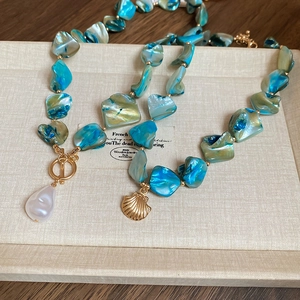 Detail of irregular blue and gold bead necklaces with baroque pearl and shell pendants