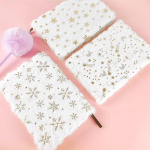 Close-up of plush white notebook covers with gold foil star, moon, and snowflake patterns