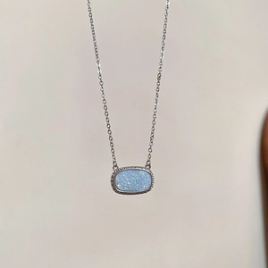Detail of blue druzy oval pendant with silver textured border on minimalist chain
