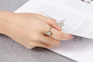 Detail shot of a silver flower-shaped ring with a clear zircon stone on a female hand
