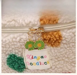 Close-up of plush fleece bag with gold double zippers and daisy flower charms detail