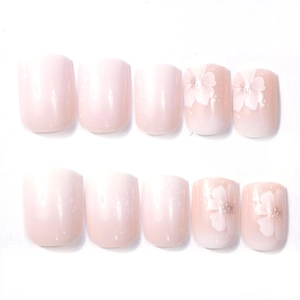 Detail of short square press-on nails with pink gradient and white floral nail art