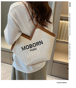 Detail of a woven tote bag in cream white and brown leather handles worn by a model
