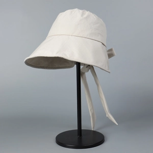Detail of cream-white bucket hat featuring back slit design and decorative ribbon tie