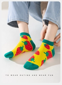 Close-up of low cut socks featuring vibrant strawberry patterns and green ribbed cuffs