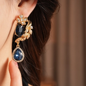 Gros plan de boucles d'oreilles vintage dorées avec gemmes bleues sur mannequin